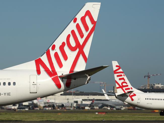 The Virgin Australia Holdings Ltd. logo is displayed on the tails of a Boeing Co. 737-800, left, and a Boeing Co. 737-8FE aircraft preparing to take off at Sydney Airport in Sydney, Australia, on Monday, Feb. 8, 2016. Virgin Australia is scheduled to announce half-year earnings on Feb. 11. Photographer: Brendon Thorne/Bloomberg