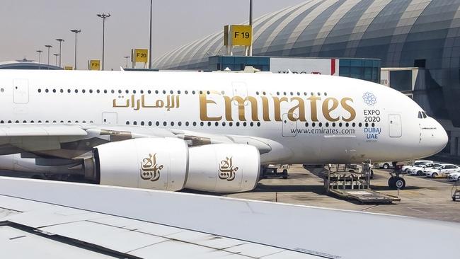 Dubai, UAE - August 9, 2015: As one Emirates Airbus A380 departs busy Dubai Airport, a similar aircraft in the next bay (F19) is framed in the passenger window as it is being prepared for its next flight.