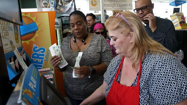 Johanna McDaniel, right, sells Powerball tickets at Kavanagh Liquors on January 13, 2016 in San Lorenzo, California. Dozens of people lined up outside of Kavanagh Liquors, a store that has had several multi-million dollar winners.