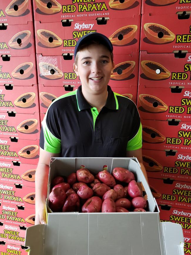 Tablelands to Tabletops worker Matthew Nason holding one box of red potatoes.