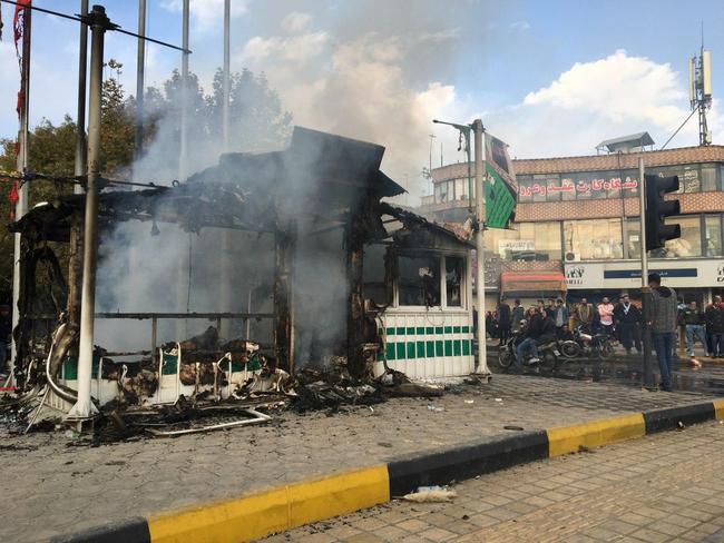 Iranians gather around a charred police station that was set ablaze by protesters during a demonstration against a rise in gasoline prices in the central city of Isfahan on November 17, 2019. - President Hassan Rouhani warned  that riot-hit Iran could not allow "insecurity" after two days of unrest killed two people and saw authorities arrest dozens and restrict internet access. Rouhani defended the controversial petrol price hike that triggered the protests -- a project which the government says will finance social welfare spending amid a sharp economic downturn (Photo by - / AFP)