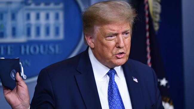 President Donald Trump holds a face mask during a press conference earlier this year, and today has tested positive for COVID-19. Picture: AFP