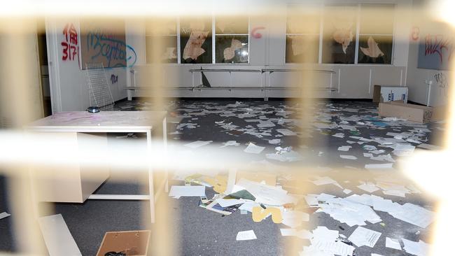 Paper is strewn on the floor of a vandalised classroom.