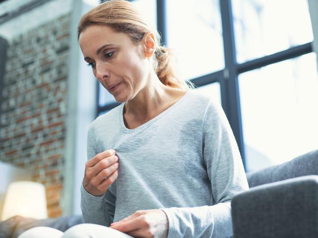 Gradual process. Beautiful mature woman touching sweater and having hot flash