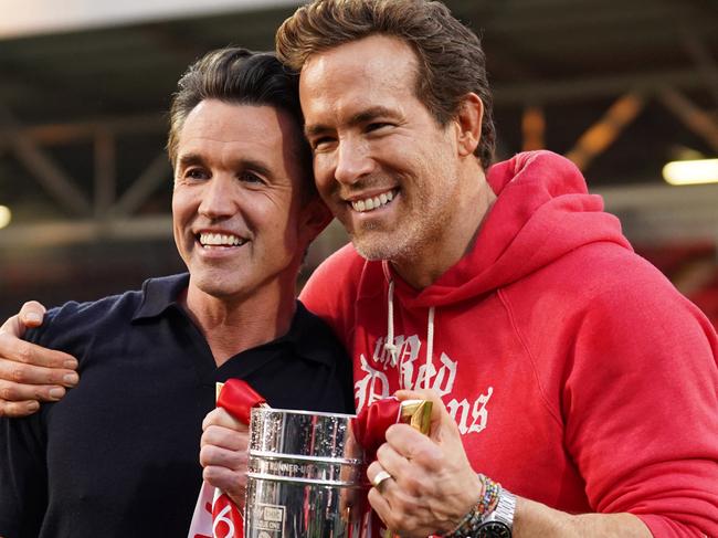 WREXHAM, WALES - APRIL 26: Rob McElhenney and Ryan Reynolds, co-owners of Wrexham AFC, pose for a photo with the trophy following the club's promotion to the Sky Bet Championship during the Sky Bet League One match between Wrexham AFC and Charlton Athletic FC at Racecourse Ground on April 26, 2025 in Wrexham, Wales. (Photo by Kya Banasko/Getty Images)