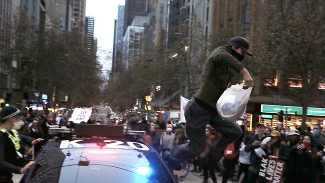 A protester runs across a police car at the Melbourne protest. Picture: Wayne Ludbey