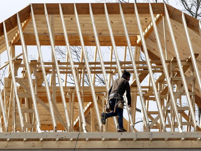 A construction worker walks along a roof on a new home.