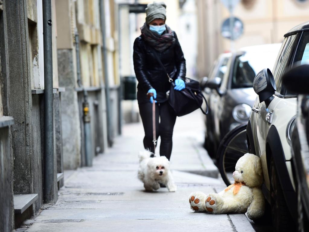 A woman wearing a face mask and gloves walks a dog in Turin, Italy. Picture: REUTERS/Massimo Pinca