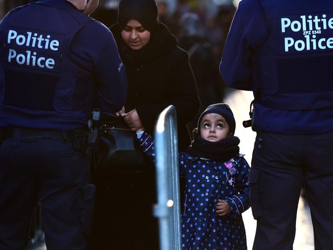 Reign of fear ... Police officers pat down a woman before entering a square to take part in a candle light vigil to the victims of the Paris attacks in Brussels' Molenbeek district. Source: AP