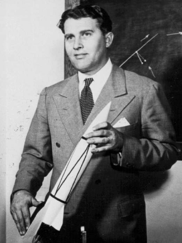 Rocket pioneer Wernher von Braun holidng a model of a V-2 rocket.