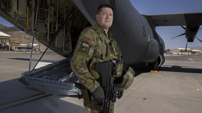 The last Australian senior Army officer to leave Afghanistan — Brigadier Todd Ashurst, the Australian Task Group Afghanistan Commander — boards a RAAF C130 aircraft, holding an Australian flag. Picture: Gary Ramage.