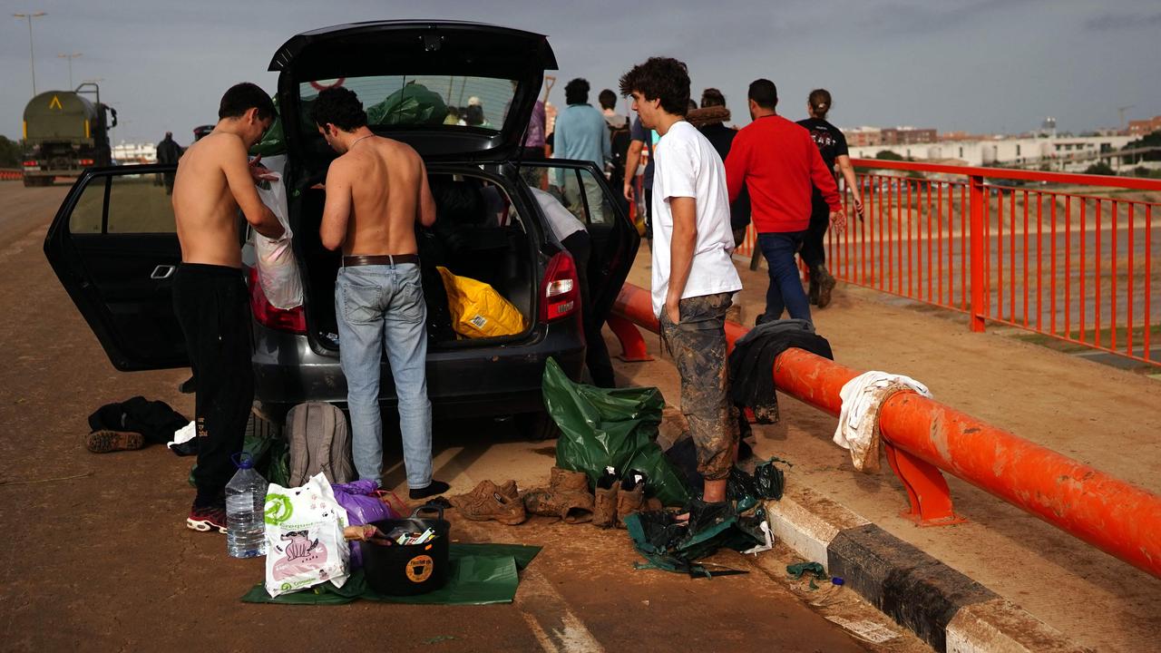 Volunteers change their clothes by the roadside prior to leaving Paiporta on November 3. Picture: Manaure Quintero/AFP