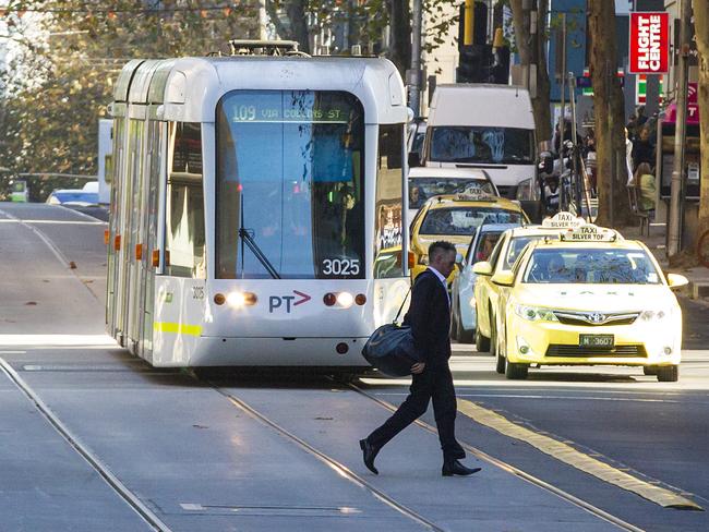 A pedestrian runs in front of a tram on Collins St. Picture: Sarah Matray