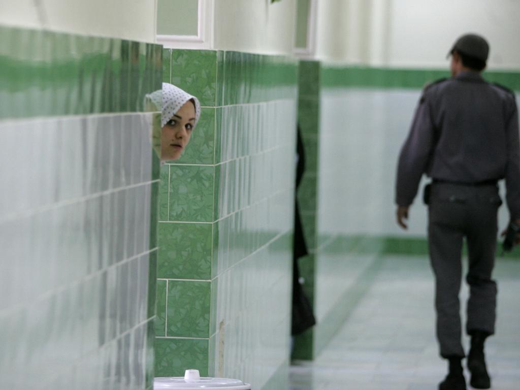 A prisoner looks at a photographer as a guard patrols the female section of the Evin jail. Picture: Atta Kenare/AFP