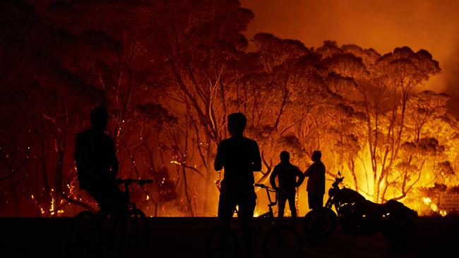 People look on as flames burn through the bush at Lake Tabourie, on the south coast. Picture: Brett Hemmings/Getty Images