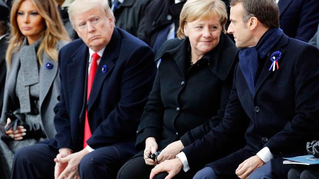 French President Emmanuel Macron (R) touches the knee of German Chancellor Angela Merkel (2nd R) as they sit next to US President Donald Trump (2nd L) and US First Lady Melania Trump (L) at the armistice service.