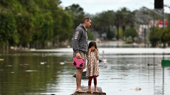 A father and his young daughter inspect a flooded street in Lismore on March 31, 2022. Picture: Dan Peled/Getty Images