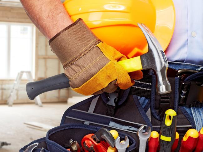 Builder handyman with construction tools. House renovation background.