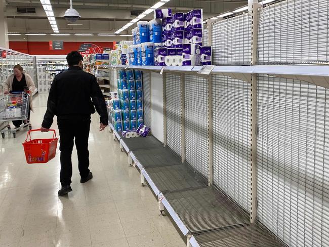 A shopper walks past near-empty shelves of toilet paper at a supermarket in a Melbourne on June 26, 2020. - Supermarkets imposed purchase limits on toilet paper across Australia on June 26 following panic buying by people rattled over a surge in coronavirus cases in the country's second-biggest city. (Photo by William WEST / AFP)