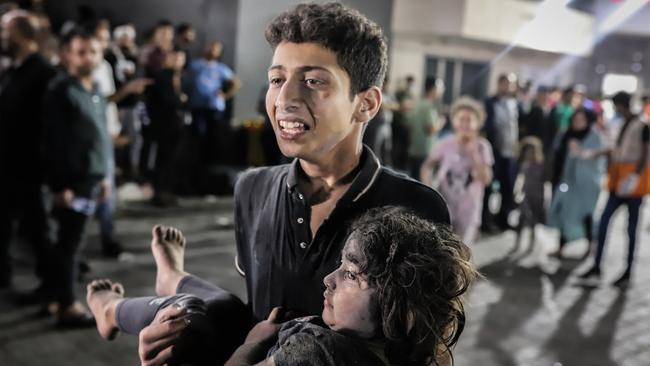 A Palestinian young man carries a child injured in an shelling on the Ahli Arab hospital, to al-Shifa hospital in Gaza City.