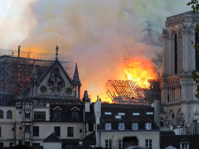 Flames and smoke are seen billowing from the roof at Notre-Dame Cathedral in Paris on April 15, 2019. - A fire broke out at the landmark Notre-Dame Cathedral in central Paris, potentially involving renovation works being carried out at the site, the fire service said.Images posted on social media showed flames and huge clouds of smoke billowing above the roof of the gothic cathedral, the most visited historic monument in Europe. (Photo by LUDOVIC MARIN / AFP)