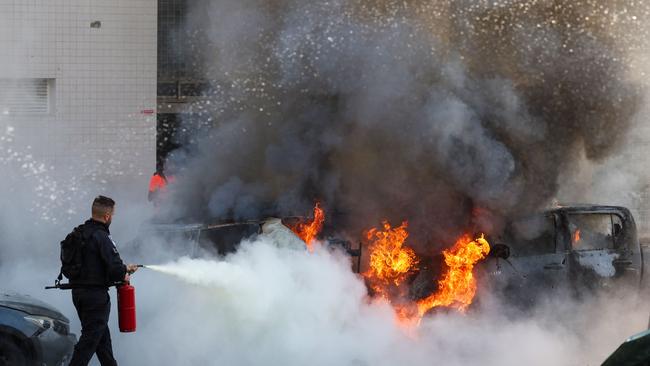 A member of Israeli security forces tries to extinguish fire on cars following a rocket attack from the Gaza Strip in Ashkelon, southern Israel. Picture: AFP