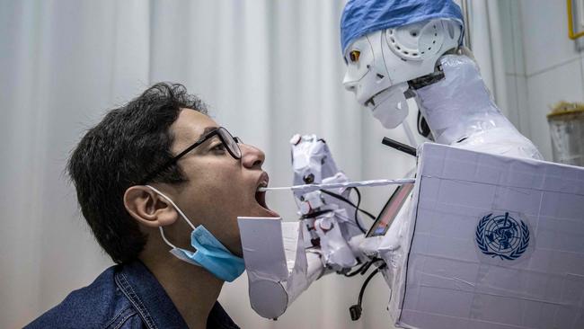 A prong extending from a remote-controlled robot prototype approaches the mouth of a volunteer to extract a throat swab sample at a hospital in Egypt's Nile delta city of Tanta. Picture: AFP