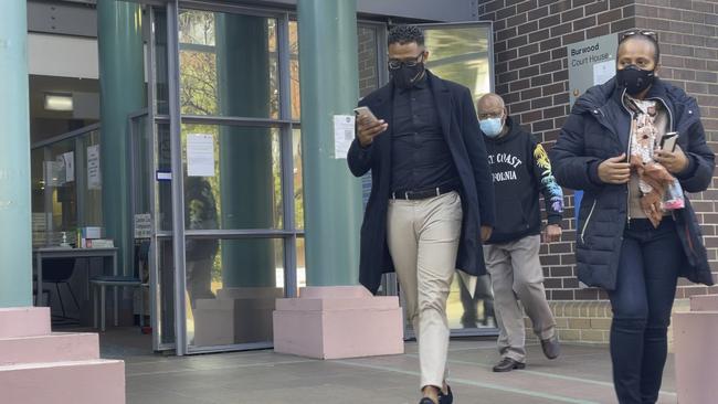 Renold Quinlan, 32, (in Nike mask) leaves Burwood Local Court on Friday with two supporters.