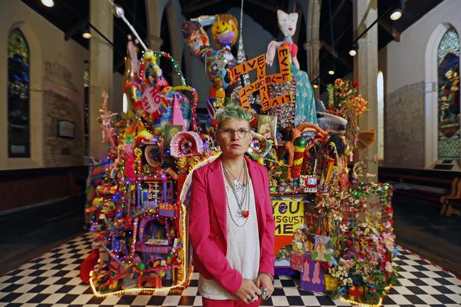 Paul Yore with his kaleidescopic rainbow-coloured sculptural temple within a church, constructed of found objects, toys, hand-made tapestry, sequins, and more. Picture: MATT THOMPSON