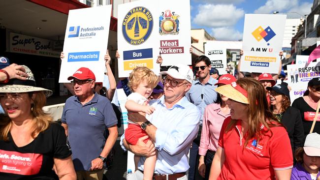 Anthony Albanese holds Oshie, the young son of MP for Lilley Anika Wells (right) during the Labour Day march in Brisbane. Picture: NCA NewsWire / Dan Peled