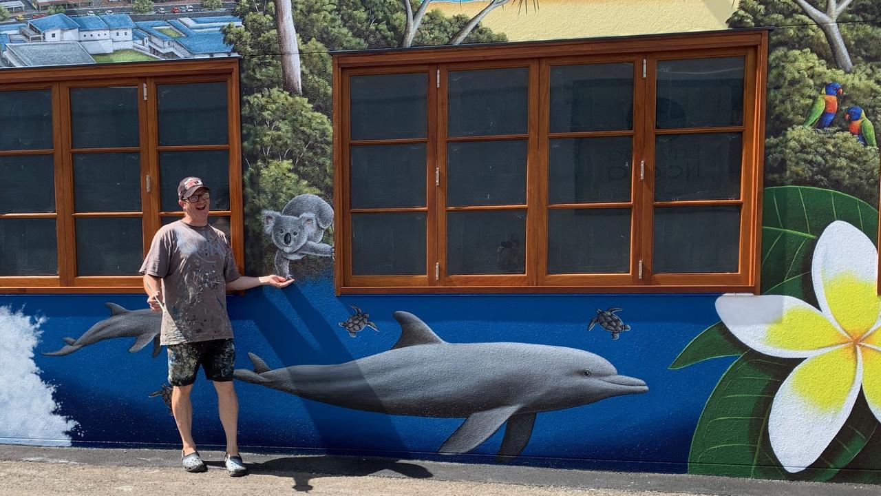 Andrew Grassi shakes paws with a koala on his new mural in Thomas St in Noosaville.