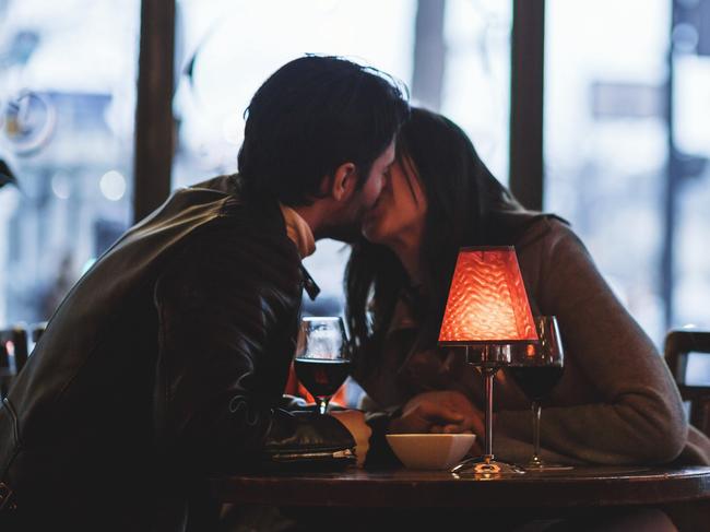 Two lovers are kissing in city cafe. They are enjoying this special moment of togetherness.