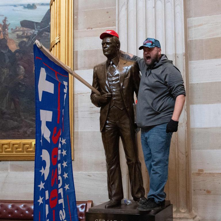 A Trump supporter poses with a statue with Trump regalia. Picture: Saul Loeb / AFP