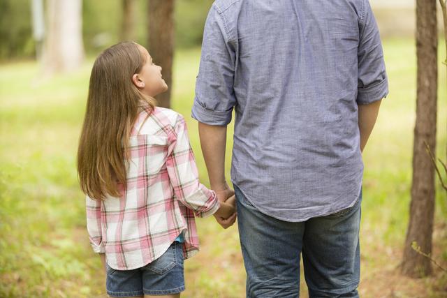 Father, daughter hold hands outdoors. Parent, child. Love, affection.