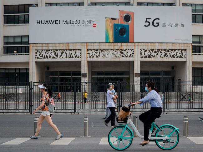 A billboard (top) featuring a commercial for Chinese telecom brand Huawei displaying their new 5G smartphones is seen as people passes by on a street in Beijing on May 22, 2020. (Photo by NICOLAS ASFOURI / AFP)