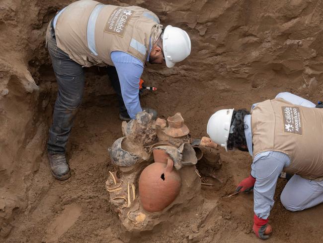 Archaeologists recover ancient human remains and artifacts discovered by workers excavating a street in a rural area in the northern district of Carabayllo in Lima, on September 22, 2023. A work crew excavating a street in Lima to lay gas pipes found eight funerary bundles, including six children from a pre-Hispanic culture 800 to 1,000 years old, also containing pottery vessels and figurines. (Photo by Cris BOURONCLE / AFP)