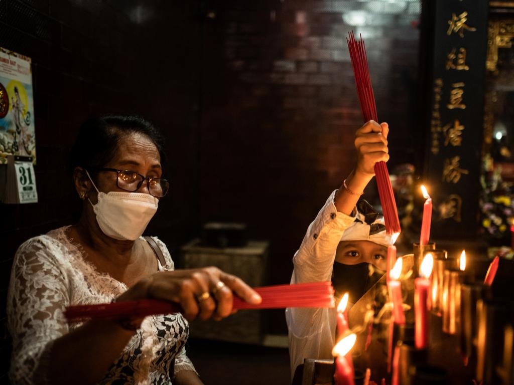 Balinese Chinese woman with her grandchildren burn incenses for prayer to celebrate Chinese New Year in Kuta, Bali, Indonesia. Picture: Getty Images