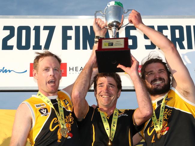 Frankston YCW coach Wayne Capp and co-captains Jie Coghlan and Kevin Lylak hold up the premiership cup in 2017. Picture: Mark Dadswell