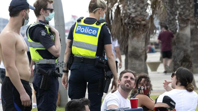 Police officers patrol among beachgoers at St Kilda on a Saturday afternoon to ensure they are wearing masks and obeying distancing rules. Picture: NCA NewsWire/David Geraghty