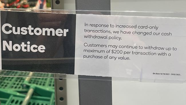 A sign above a Woolworths self service checkout informs customers about the new cash withdrawal limit.