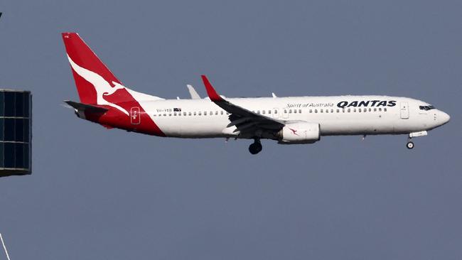 This picture taken on December 6, 2023 shows a Qantas Airways Boeing 737-800 passenger aircraft on final approach for landing in front of the control tower at Sydneyâs Kingsford Smith international airport. (Photo by DAVID GRAY / AFP)