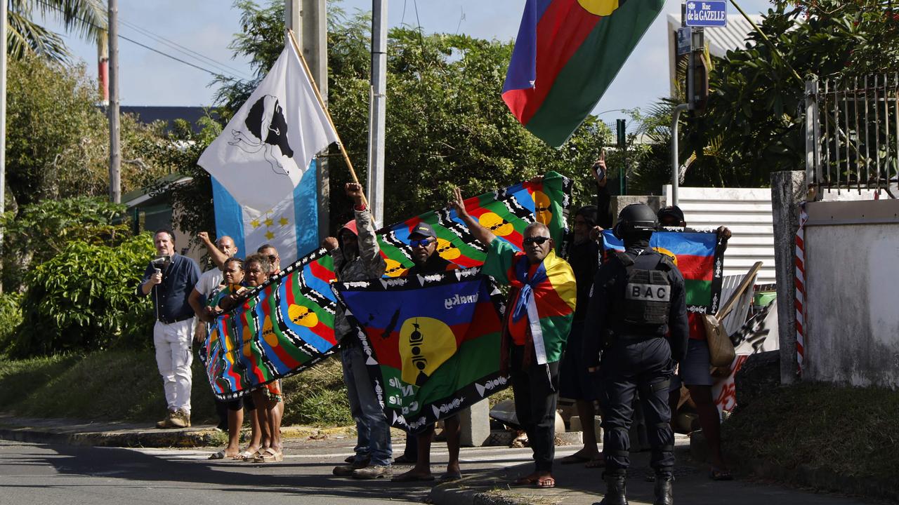 New Caledonians demonstrate against changes to New Caledonia’s voting system as French President Emmanuel Macron's motorcade drives past in Noumea. Picture: Ludovic Marin/POOL/AFP