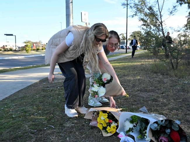 Two women lay flowers on the side the road some 500 meters from the site of a bus crash. Picture: Saeed KHAN / AFP