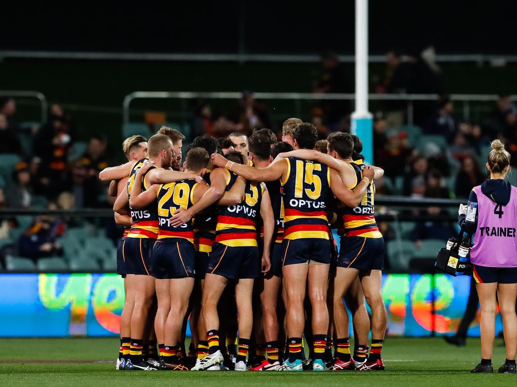 The Crows players huddle up in the middle of Adelaide Oval.