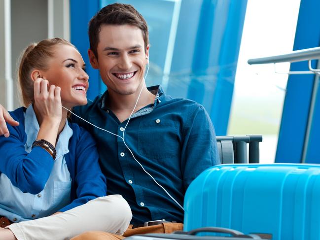 Young couple waiting for their flight at the airport lounge and listening to the music. Picture: iStock.