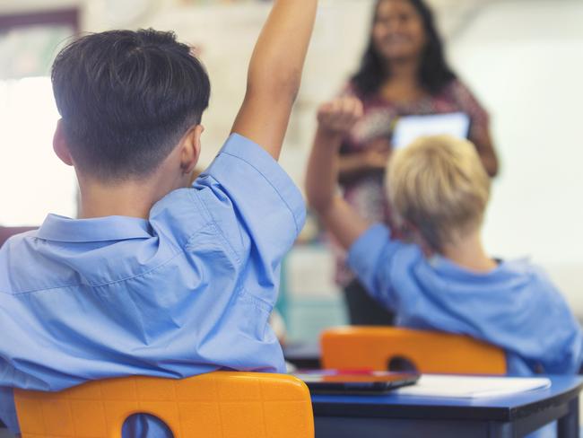 Aboriginal Elementary school  teacher giving a presentation to the class. The students have their hands raised to ask  questions in the classroom  Picture: istock