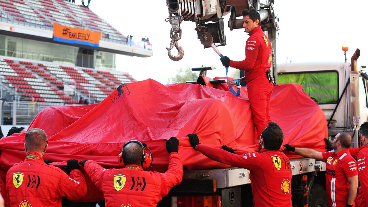Mechanics help lift the car of Sebastian Vettel after it broke down on day three.