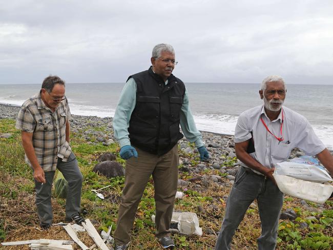 Mystery ... A Malaysian expert (centre) looks for debris from the ill-fated Malaysia Airlines flight MH370 on a beach in Saint-Andre de la Reunion, on the French Reunion Island. Picture: AFP/ Richard Bouhet