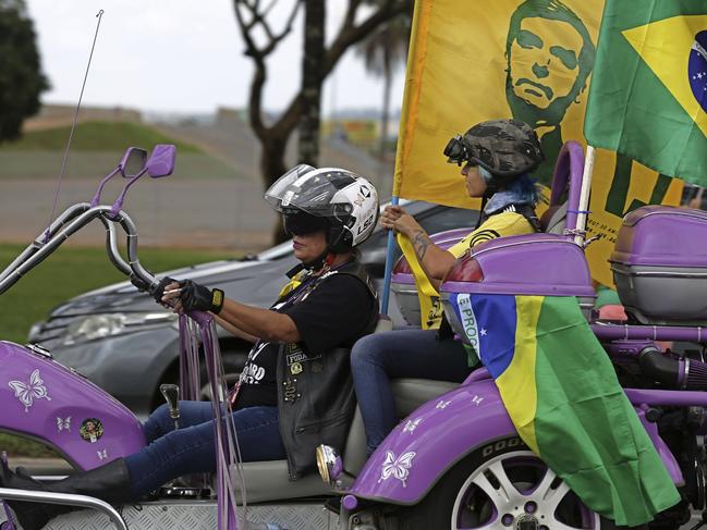 Mother and daughter carry flags on their tricycle during a rally in support of right-wing presidential candidate Jair Bolsonaro, in Brasilia, Brazil, Saturday, Oct. 27, 2018. Brazil is preparing for general elections to be held Sunday, Oct. 28. (AP Photo/Eraldo Peres)