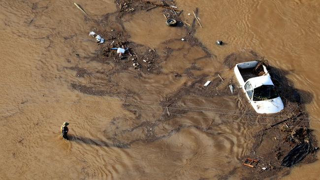 Police officers search the wreckage after severe floods hit Grantham in the Lockyer Valley, Queensland.